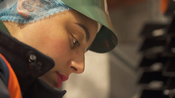 Close up of a woman's face. She is wearing a hairnet and hat.