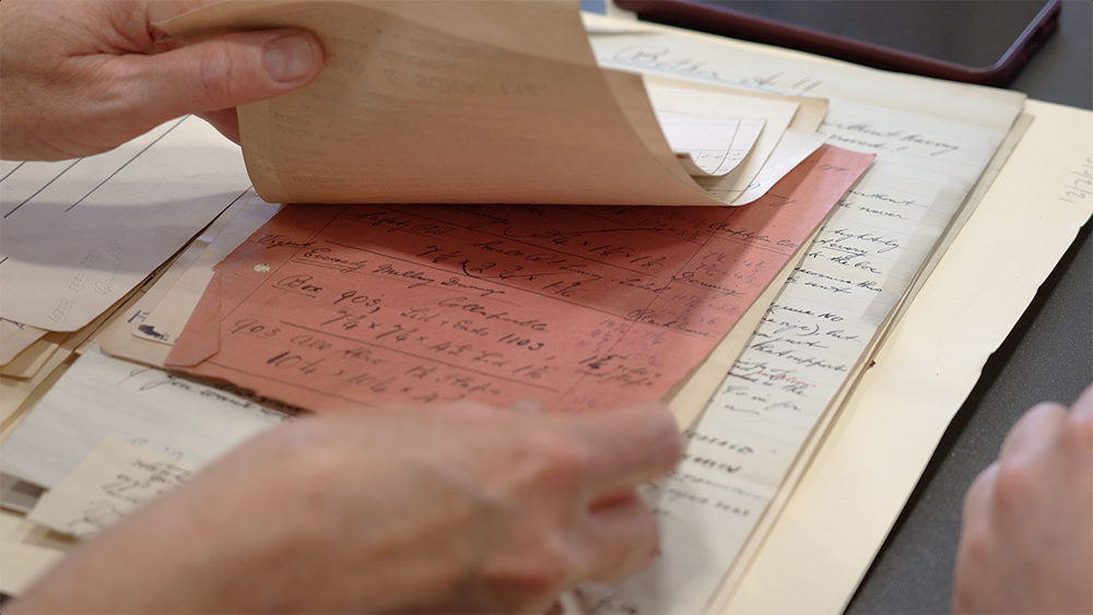 Close up of hands rifling through old company records.