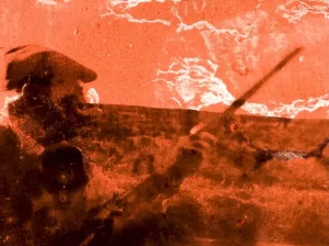A man with a flat cap and shotgun on a moorland. The image is tinted orange.